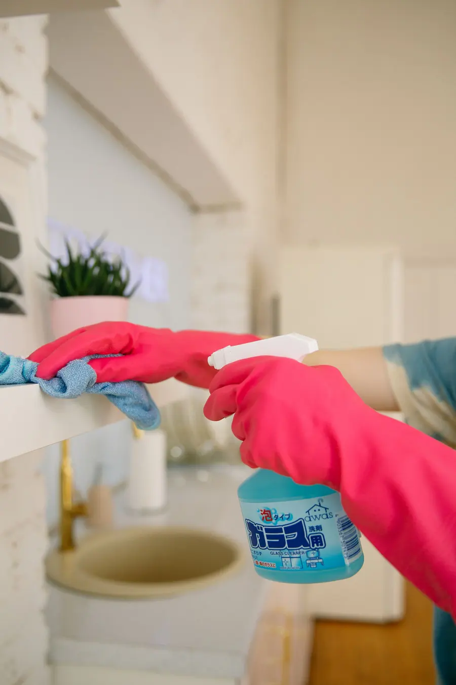 Hand met spuitfles en doek bij het ontsmetten van een woning